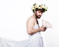 Bearded man in a woman`s wedding dress on her naked body, holding a flower. on his head a wreath of flowers. funny Royalty Free Stock Photo