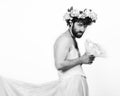 Bearded man in a woman`s wedding dress on her naked body, holding a flower. on his head a wreath of flowers. funny Royalty Free Stock Photo