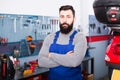 bearded man worker displaying his workplace in motorcycle workshop Royalty Free Stock Photo