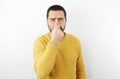 Bearded man with yellow shirt on isolated white background plugs the dwarf with his fingers. Royalty Free Stock Photo