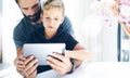 Bearded man with young boy using tablet PC in sunny room.Dad and little son playing together on mobile computer, resting Royalty Free Stock Photo