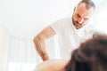 Bearded Masseur man doing massage manipulations on the low back area during young female body massaging. Health care concept image Royalty Free Stock Photo