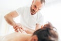 Bearded Masseur man doing massage manipulations on the Scapula area zone during young female body massaging Royalty Free Stock Photo