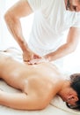 Bearded Masseur man doing massage manipulations on the Scapula area zone during young female body massaging Royalty Free Stock Photo