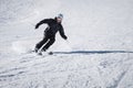 A bearded mature aged male skier in a black ski suit descends along the snowy slope of a ski resort. The concept of