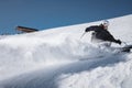 A bearded mature aged male skier in a black ski suit descends along the snowy slope of a ski resort. Sedation on the