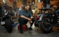 Bearded mature man biker cleaning motorcycle in garage workstation