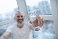 A bearded mature man holding a glass with water