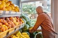 bearded mature salesman putting fresh watermelons