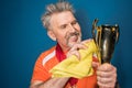 Bearded mature sportsman cleaning trophy cup