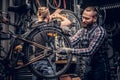 Mechanic doing bicycle wheel service manual in a workshop. Royalty Free Stock Photo