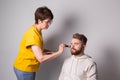 Bearded man getting makeup. Woman visagist works with brush.