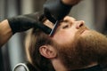 Bearded man with long beard getting stylish hair shaving , haircut , with razor by barber in barbershop