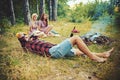 Bearded man in lumberjack shirt lying on grass and looking into the sky, unity with nature concept. Group of friends Royalty Free Stock Photo