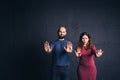 Bearded man and pregnant woman show hands stop in studio on dark background. Copy space.