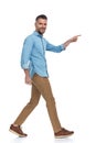 Bearded middle aged guy smiling and pointing finger while walking