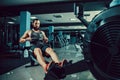 Muscular fit man using rowing machine at gym Royalty Free Stock Photo