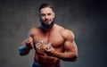 Bearded bodybuilder eating his diet in gray background
