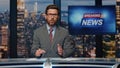 Bearded newscaster ending program in evening newsroom studio. Late breaking news Royalty Free Stock Photo