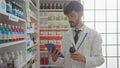 Bearded pharmacist using tablet searches medication in modern drugstore Royalty Free Stock Photo