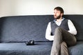 Bearded photographer sitting on a couch wearing a grey vest.