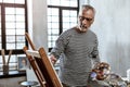 Bearded professional artist working in light spacious workshop