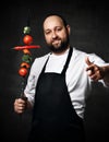 Bearded professional chef in white skirt and apron invites to eat vegetables on a skewer kebab Royalty Free Stock Photo