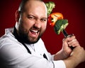 Bearded professional chef in white skirt going to fight with skewer with vegetables on it kebab Royalty Free Stock Photo