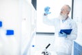 Bearded scientist holding flask with reagent and clipboard in chemical lab