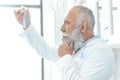 Bearded scientist in white coat thinking and looking at tube with reagent in chemical lab