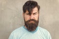 Bearded and shaggy. Bearded man with stylish haircut on grey wall. Unshaven caucasian guy wearing thick mustache and