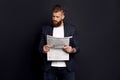 Bearded smart handsome concentrated chief dressed in jacket and shirt reading latest news from newspaper isolated on black Royalty Free Stock Photo