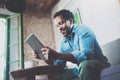 Bearded smiling African man using tablet for video conversation while relaxing on sofa in modern office.Concept of young Royalty Free Stock Photo