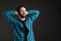 Bearded smiling man in shirt posing with hands clasped behind his neck Royalty Free Stock Photo