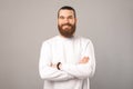 Bearded smiling man is standing in a studio with crossed arms. Royalty Free Stock Photo