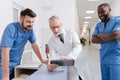 Bearded smiling practitioner enjoying conversation with colleagues at work