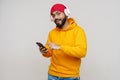 Bearded south asian man in headphones smiling and using cellphone Royalty Free Stock Photo