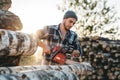 Bearded strong lumberjack wearing plaid shirt sawing tree with chainsaw for work Royalty Free Stock Photo