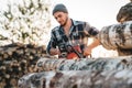 Bearded strong lumberjack wearing plaid shirt using chainsaw for work Royalty Free Stock Photo