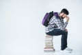 Bearded student sitting on pile of books on white with copy space
