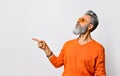 Bearded and stylish. Handsome smiling bearded man in orange sweater and sunglasses, bracelet showing direction with finger. Royalty Free Stock Photo