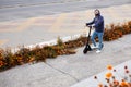 Bearded stylish man riding the electric scooter. Guy on daily commute riding micro scooter.