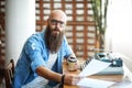 Bearded stylish writer with cup of coffe reading his novel Royalty Free Stock Photo