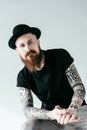 bearded tattooed man in hat looking at camera