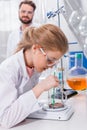 Bearded teacher looking at little student making experiment in laboratory