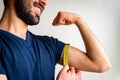 Bearded thin man measuring biceps, muscles of his left arm with a yellow tape measure. He`s smiling, happy. Royalty Free Stock Photo