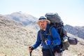 bearded tourist with a large backpack on the path to the top of the mountain