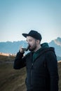 Bearded traveler man drinks tea or coffee from  metal cup while resting on a rock Royalty Free Stock Photo