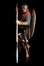 Bearded warrior in the armor and in the helmet of the Viking Age holds a shield, sword, ax and lance