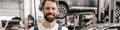 Bearded white car mechanic smiling while standing in garage